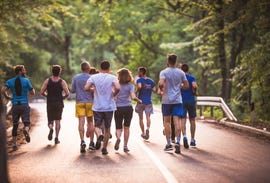 rear view of large group of runners running a marathon