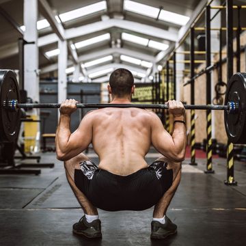 rear view of man picking up barbell in gym