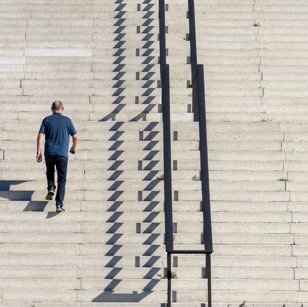 rear view of man walking on staircase during sunny day