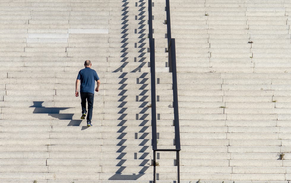 rear view of man walking on staircase during sunny day