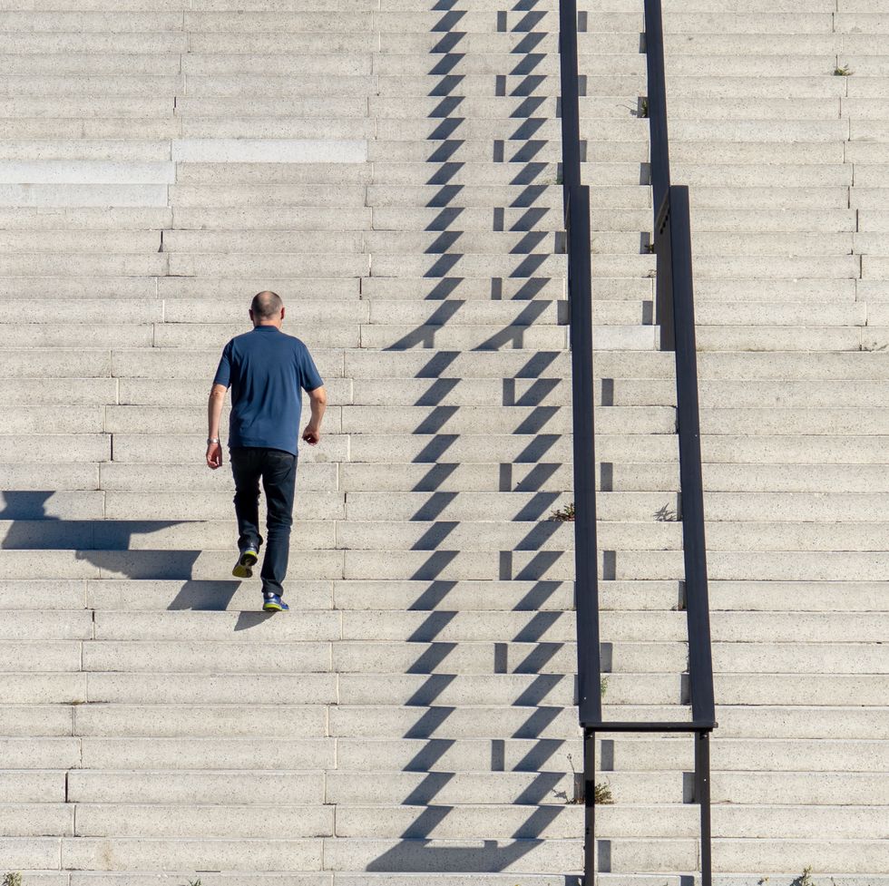 rear view of man walking on staircase during sunny day