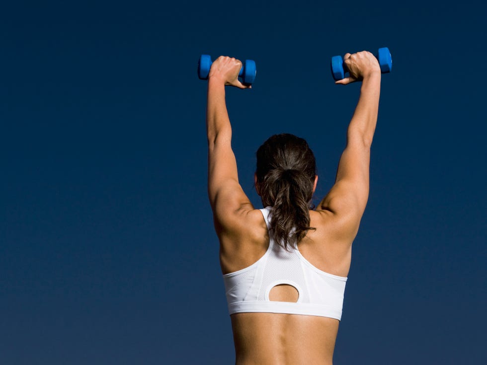 Muscular woman in gym showing back muscles. - Stock Photo