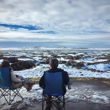 Rear View Of People Sitting On Camping Chair During Winter