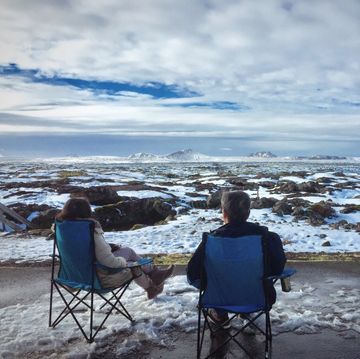 Rear View Of People Sitting On Camping Chair During Winter