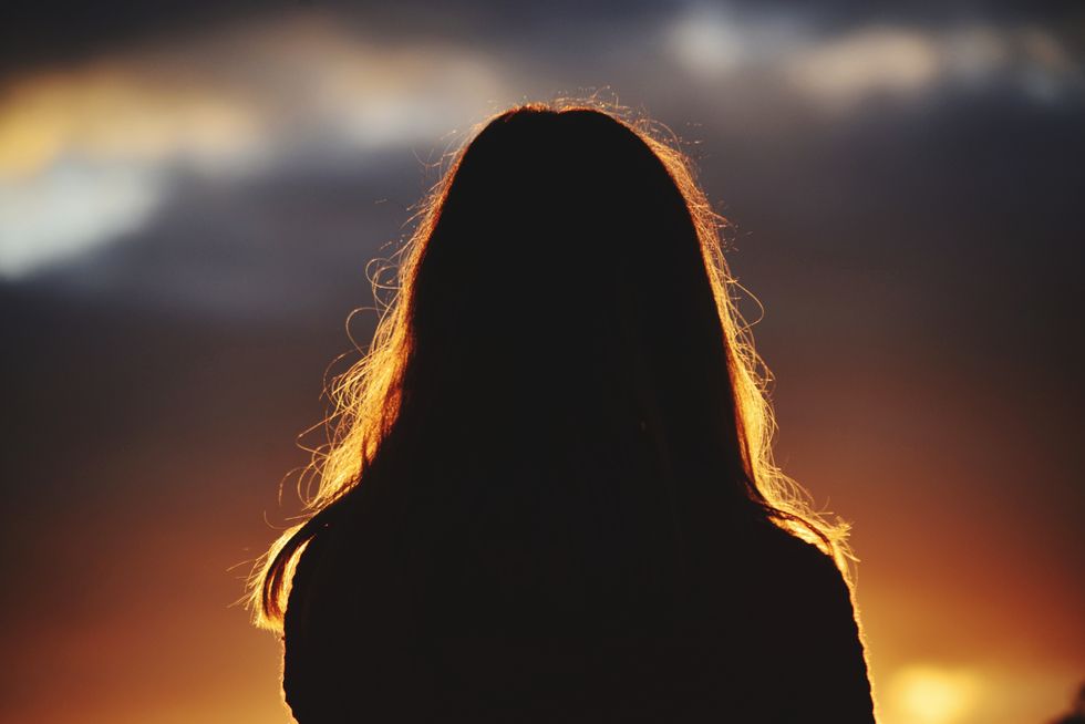 woman against dark sky at sunset