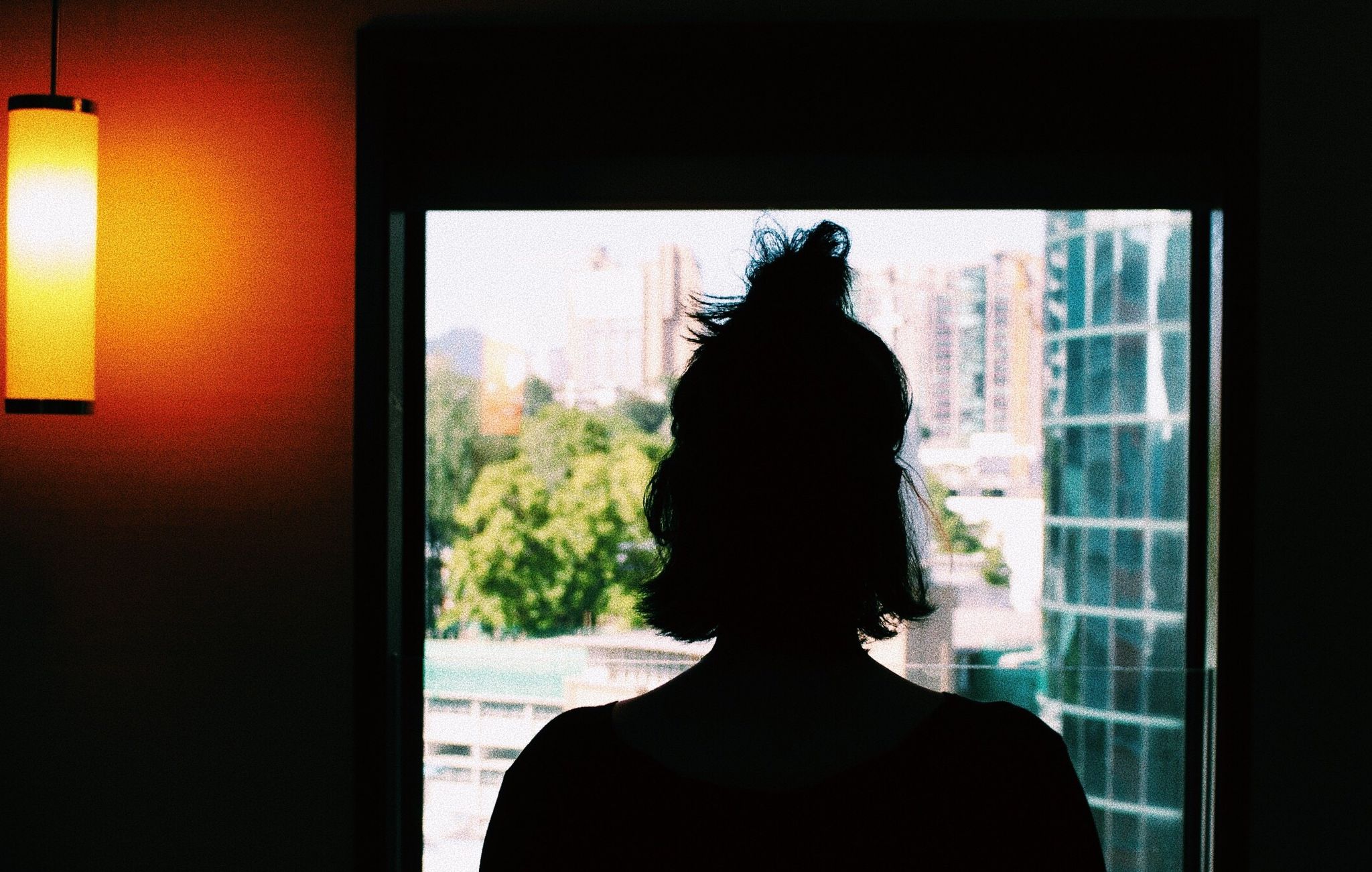 Rear View Of Silhouette Woman Looking Through Window