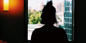Rear View Of Silhouette Woman Looking Through Window
