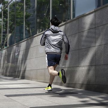 rear view of sporty young man running in city