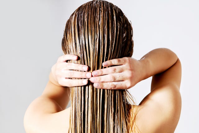 Rear View Of Woman Applying Conditioner On Hair Against White Background