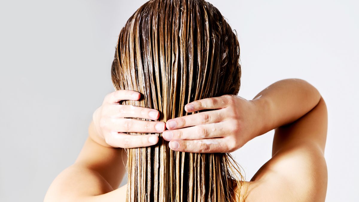 Rear View Of Woman Applying Conditioner On Hair Against White Background