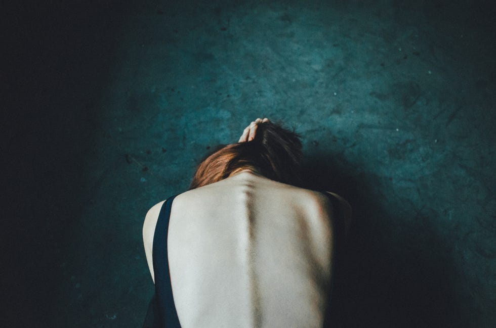 rear view of woman bending against green wall