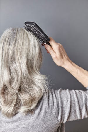 rear view of woman brushing long gray hair