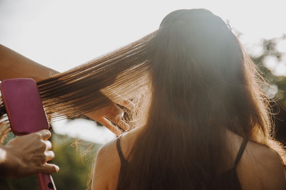 rear view of woman combing hair outdoors
