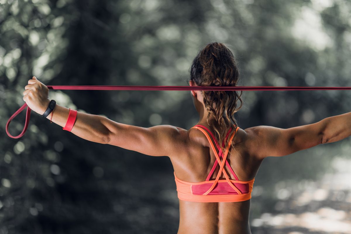 Rear View Of Woman Exercising With Resistance Band