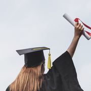 rear view of woman holding diploma against clear sky