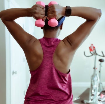 Rear View of Woman Holding Dumbbells Behind Head rear view of woman holding dumbbells behind head
