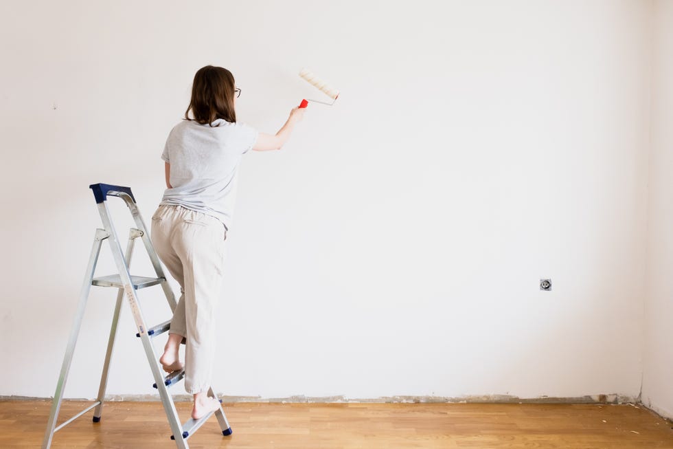 rear view of woman holding umbrella against white wall