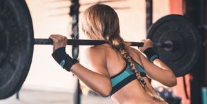 Rear View Of Woman Lifting Weights In Gym