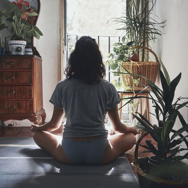 rear view of woman meditating while sitting at home