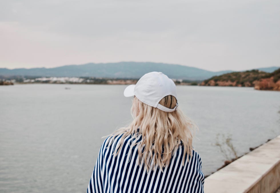 mujer con gorra mirando las vistas a la playa