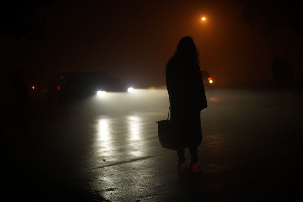 rear view of woman standing on road at night