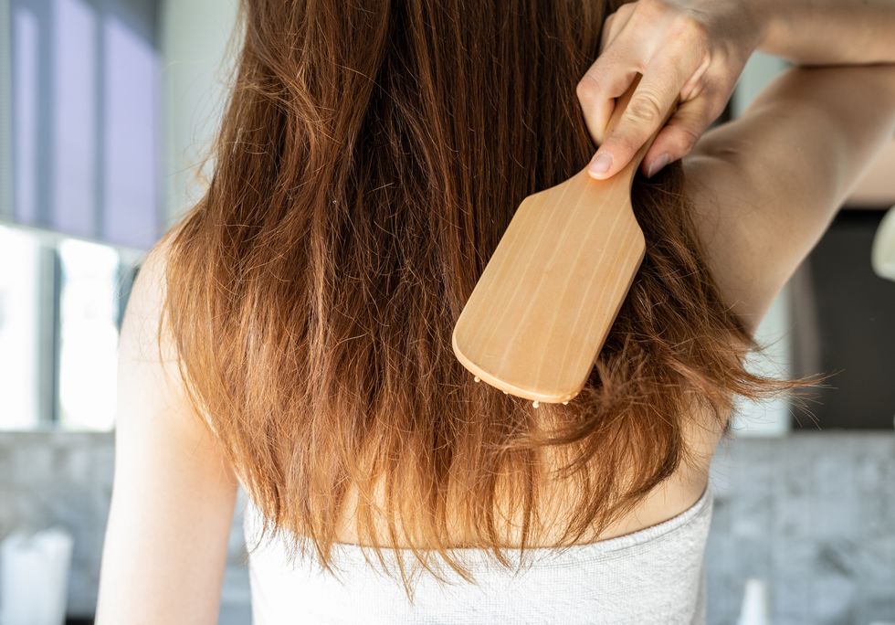 rear view of young asian woman brushing her thick hair