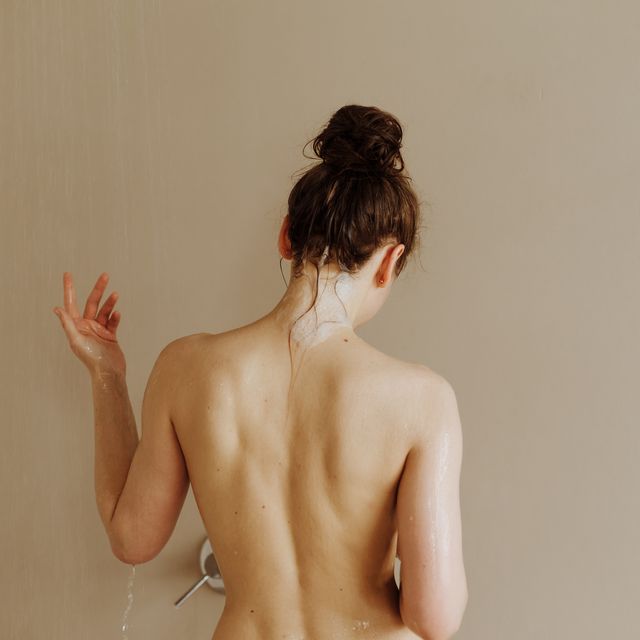 rear view of young attractive woman taking shower