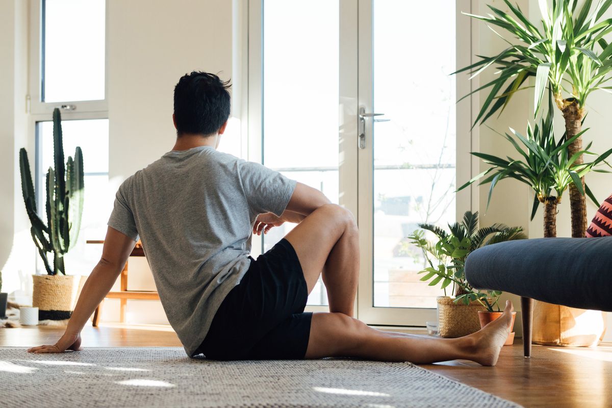 rear view of young man doing stretching exercise at home