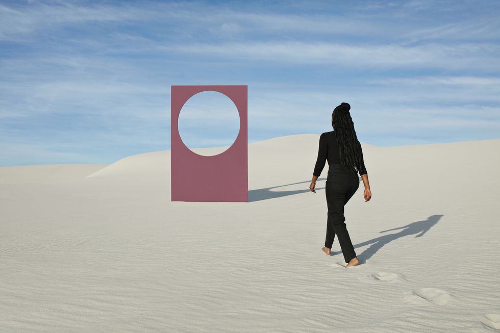 rear view of young woman walking towards portal at white desert