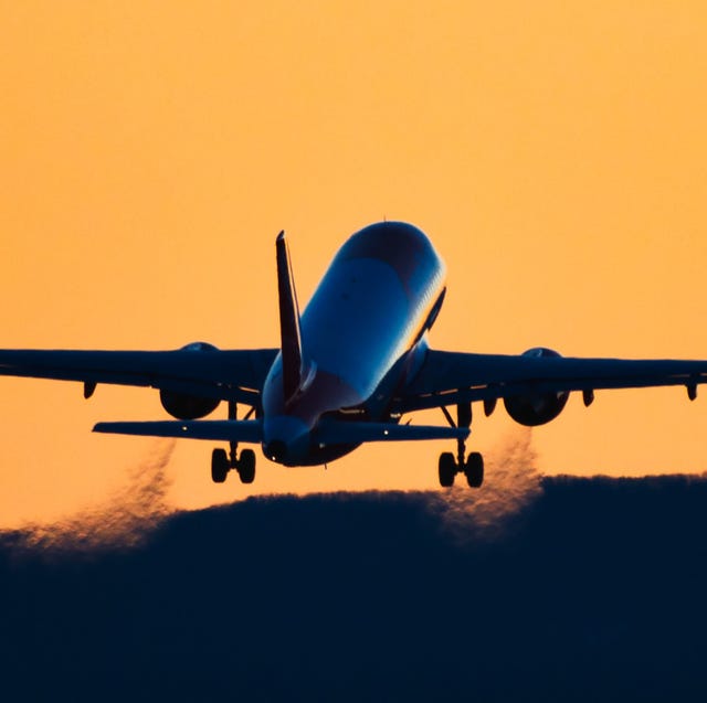 rear view silhouette of an airplane taking off at sunset