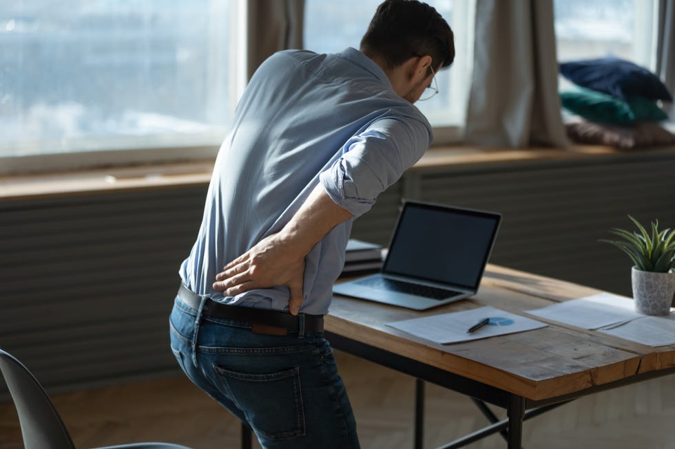 rear view young man suffering from sudden backache at workplace