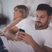 reasons for low sex drive  woman looking away in bed while man is on phone