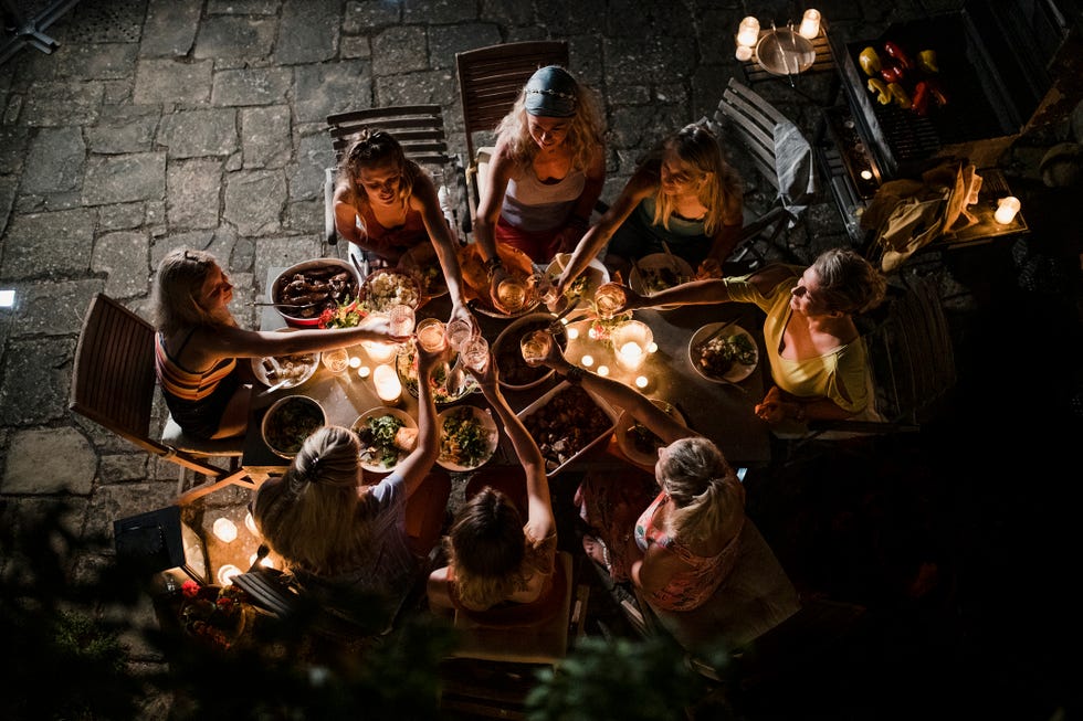 group of mixed age women are enjoying an al fresco meal in italy at dusk