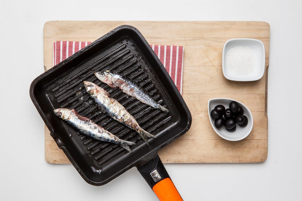 plancha con tres sardinas y un bol de aceitunas negras