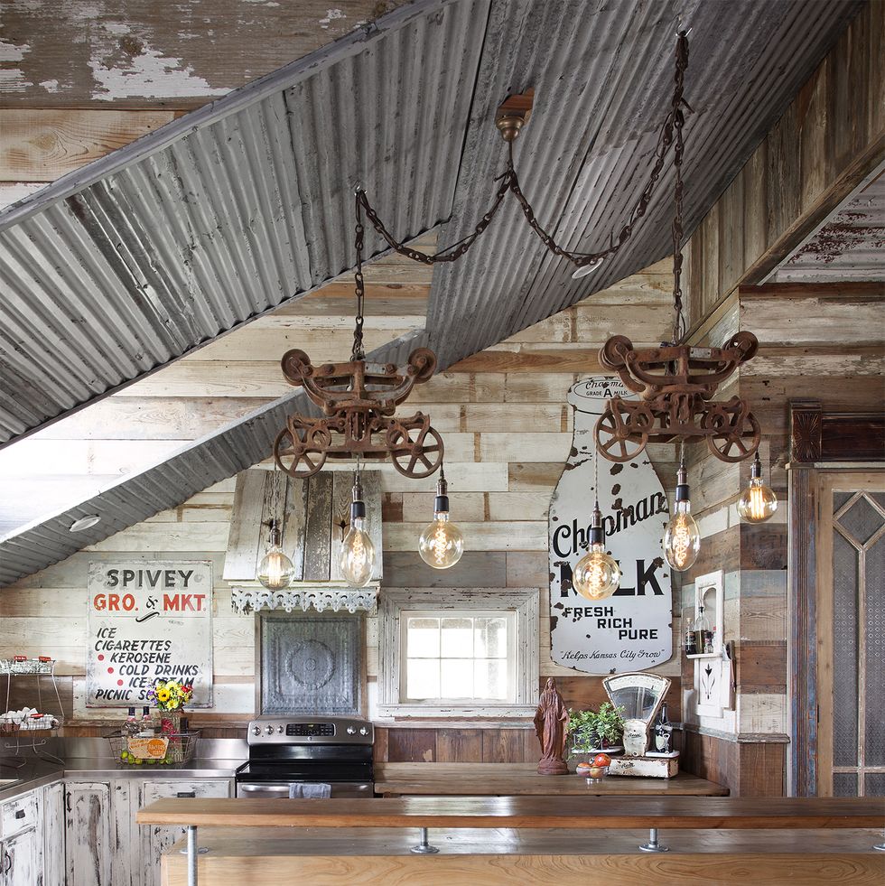 a rustic kitchen with a tin roof and reclaimed items that make the light fixtures above the island