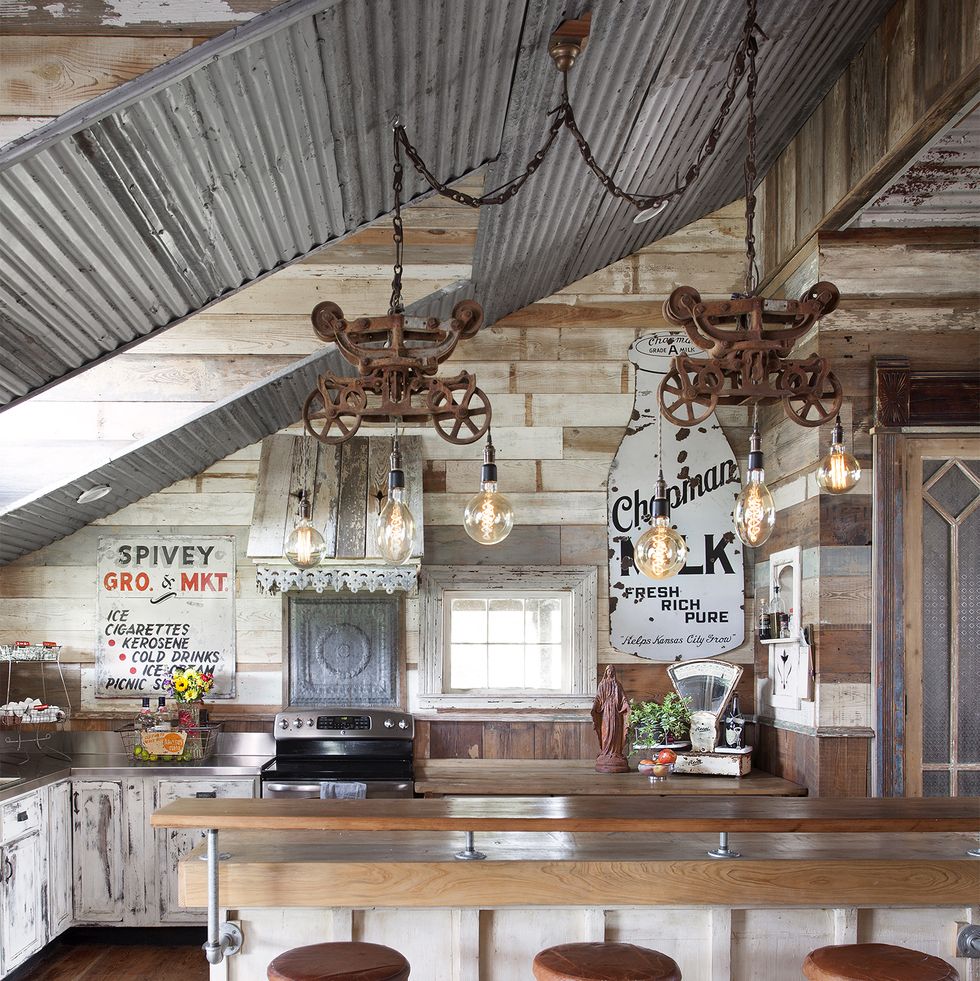 a rustic kitchen with a tin roof and reclaimed items that make the light fixtures above the island