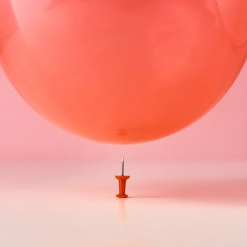 red balloon fall on a pin needle on pink background danger or protection concept