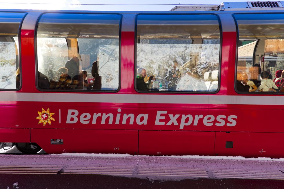 red bernina express train at railway station of rhb narrow gauge railway at swiss mountain village of filisur on a snowy autumn morning