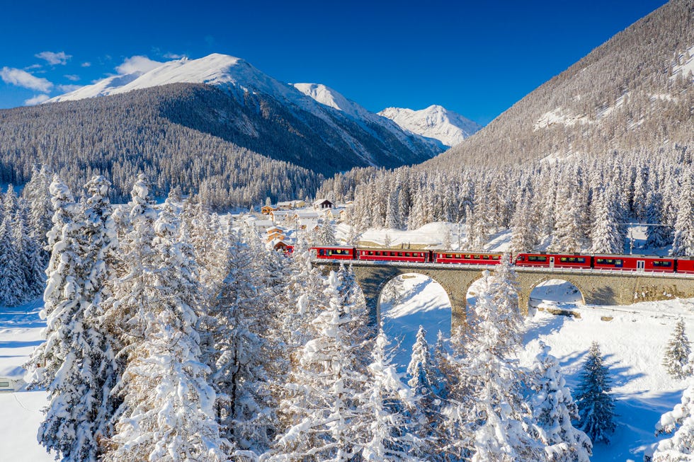 red bernina express train in the snowy landscape, chapella, switzerland