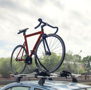 red bicycle on blue car roof mounted with racks outdoors