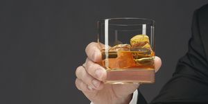 mano de hombre sujetando un vaso de whisky con hielo
