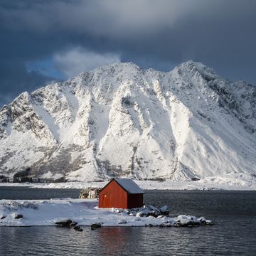 red cabin in a fjord in winter