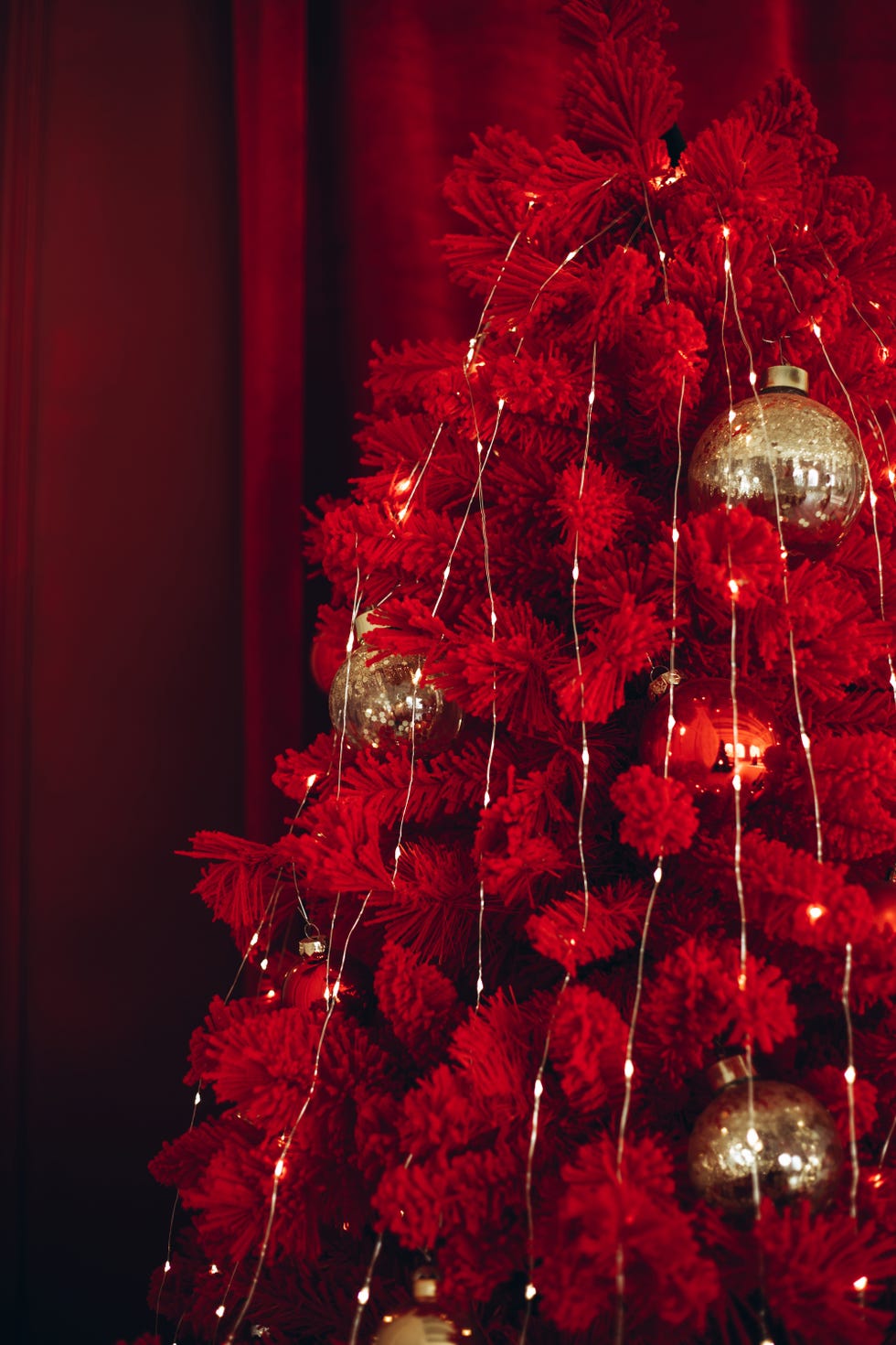 Beautiful golden and red Christmas toys hanging on a bright red Christmas tree closeup with space for text