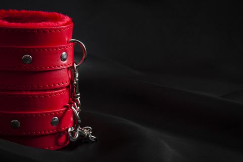 Red cuffs on black satin background with copyspace