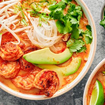 red curry soup with shrimp and noodles with avocado slices, cilantro and toppings