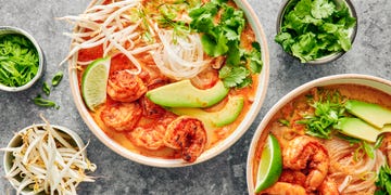 red curry soup with shrimp and noodles with avocado slices, cilantro and toppings