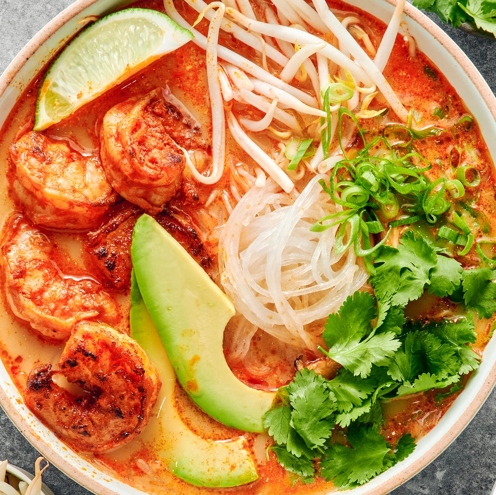 red curry soup with shrimp and noodles with avocado slices, cilantro and toppings