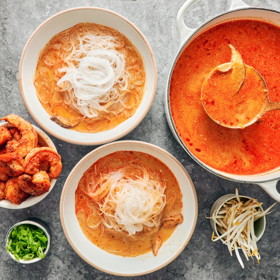 red curry soup with shrimp and noodles with avocado slices, cilantro and toppings