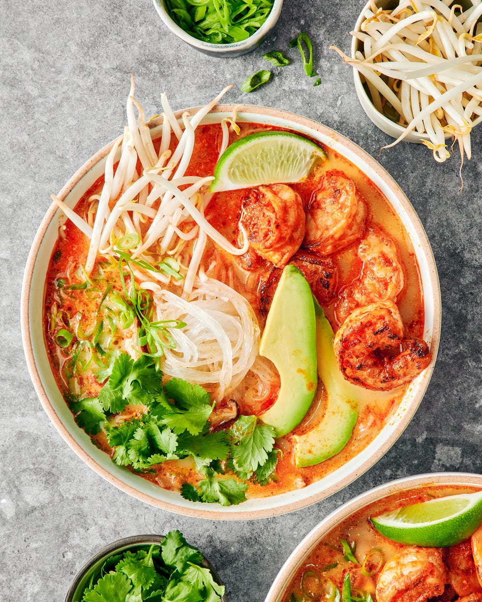 red curry soup with shrimp and noodles with avocado slices, cilantro and toppings