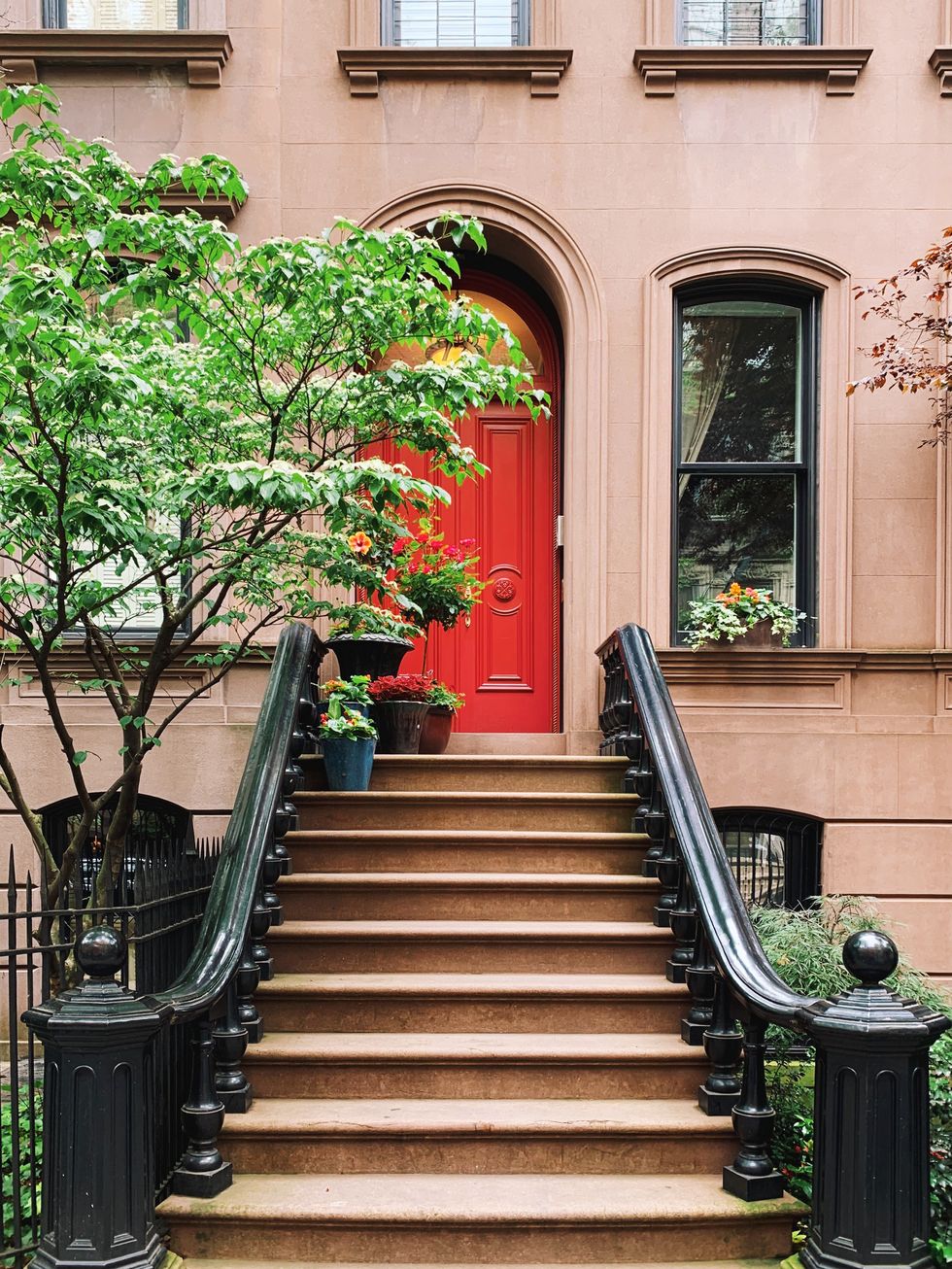 red door of a residential brownstone townhouse in west village, new york city, usa